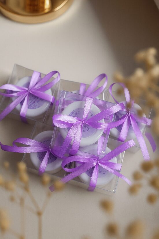 Personalizēta kāzu svece stikla burciņā viesiem ar violetu lentīti